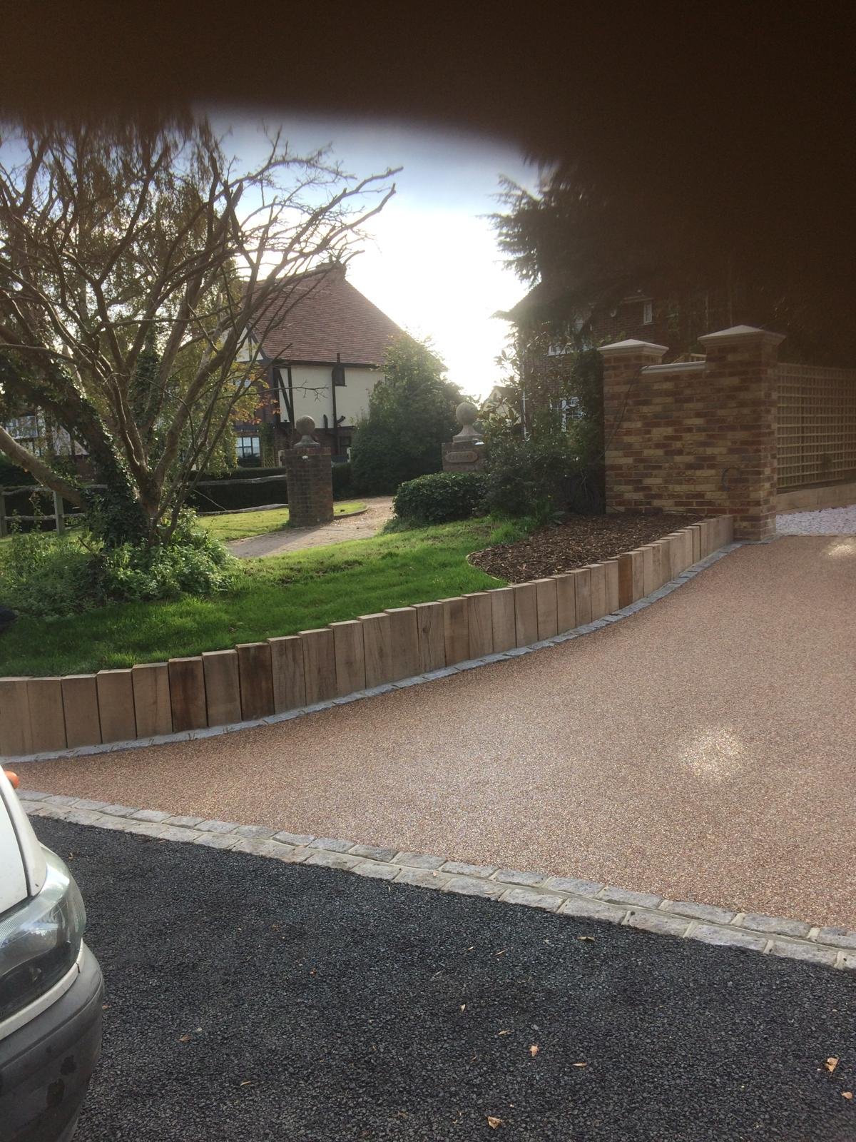 Curved resin bound driveway beside a landscaped garden and stone wall